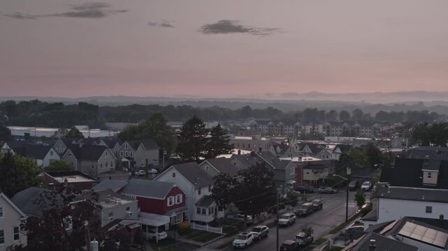 real-time aerial view over a quiet New Jersey residential neighborhood featuring family homes and quiet streets under a moody, overcast twilight sky town of East Rutherford