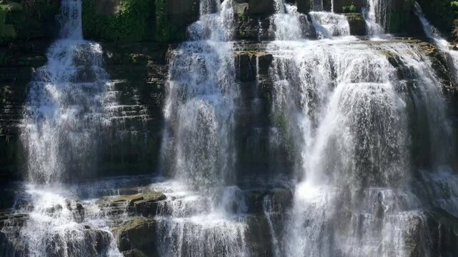 Aerial view of Cigangsa Waterfall with water cascading over tiered rock formations and lush greenery in Sukabumi, West Java, Indonesia.