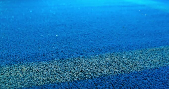 Extreme super slow motion close-up of a tennis or padel ball bouncing near the court line. Detailed blue surface texture captured at 1000fps with dynamic sports action in macro detail.