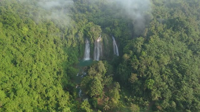 Aerial view of Cikaso Waterfall cascading through dense tropical forest with morning mist and lush greenery Sukabumi, West Java, Indonesia.
