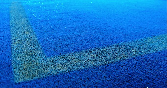 Extreme super slow motion close-up of a tennis or padel ball bouncing near the court line. Detailed blue surface texture captured at 1000fps with dynamic sports action in macro detail.
