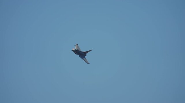 Slow motion of a delta wing canard fighter jet banking steeply against a clear blue sky, showcasing agile aerial maneuver at airshow