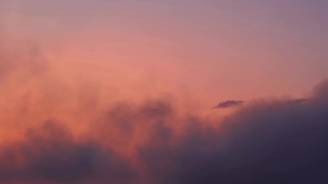 Soft pink and orange sunset sky with layered mauve clouds creating calm mood at dusk