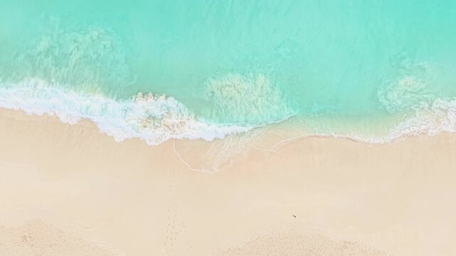 Aerial view of turquoise ocean waves washing onto the pristine white sand beach at Anse Reunion, La Digue, Seychelles.