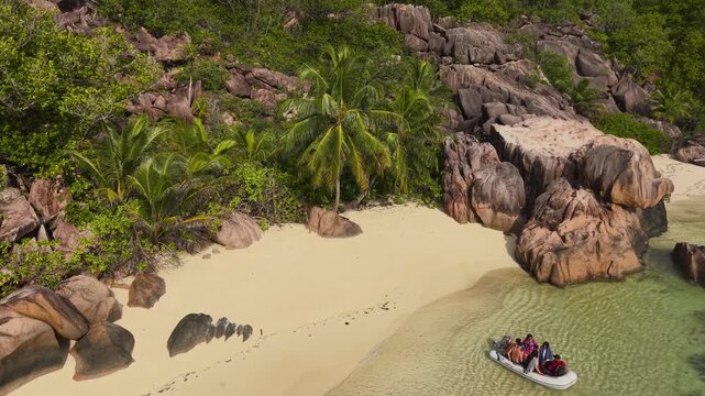 Aerial view of Anse Reunion beach featuring iconic granite rock formations, palm trees and a small boat in turquoise water Anse Reunion, La Digue, Seychelles.