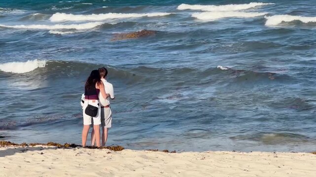 pareja se abraza a la orilla del mar en playas de Tulum