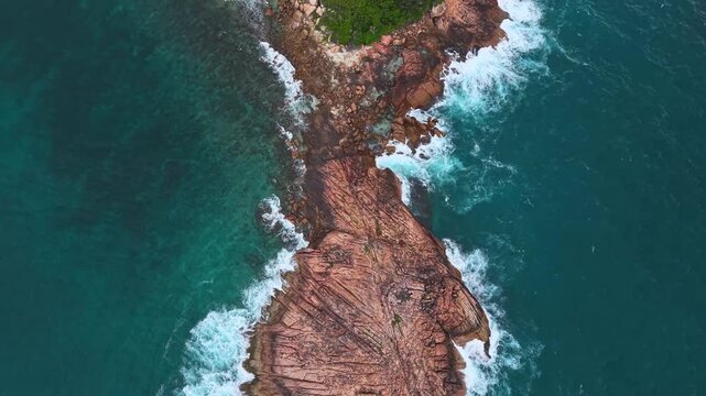 Aerial view of a large granite rock formation surrounded by turquoise ocean water and crashing white waves at Praslin, Grand Anse, Grand Anse Praslin, Seychelles.