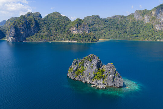 Surrounded by coral, rugged limestone islands rise from Bacuit Bay, El Nido. This area in the Philippines is a popular vacation destination due to its coral reefs, beaches, and limestone islands.