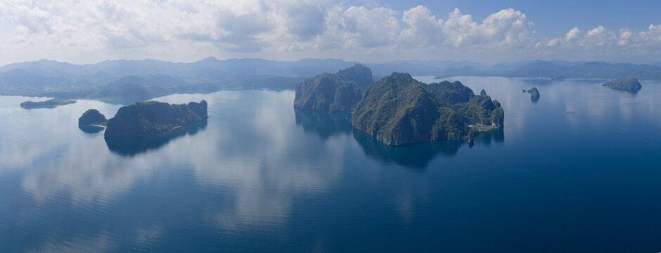 Calm water surrounds majestic limestone islands in El Nido, Philippines. This scenic area of Palawan is a popular vacation destination due to its reefs, beaches, and rock islands.