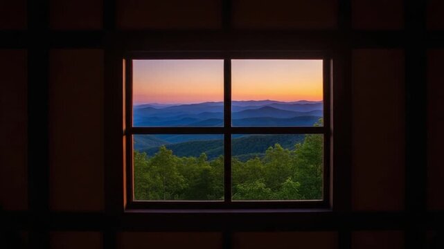 Sunset mountain view through a rustic cabin window frame looking out at rolling blue ridge hills at dusk