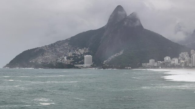 Aerial view of Ipanema Beach with Morro Dois Irmaos and the Vidigal favela under a misty sky with choppy ocean waves State of Rio de Janeiro, Brazil.