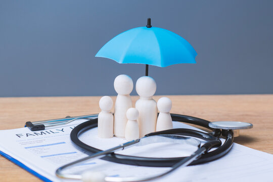 Family insurance concept with wooden figures with blue umbrella and stethoscope on policy form. Health coverage, protection, medical care and financial security for family plan and healthcare service.