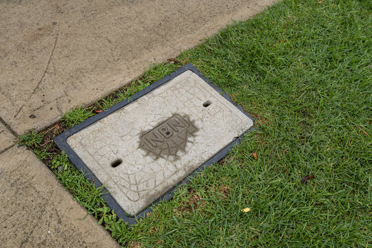 A concrete telecommunications pit cover embossed with the "NBN" (National Broadband Network) logo in suburban Melbourne Australia. Standard Australian digital infrastructure, local council utilities
