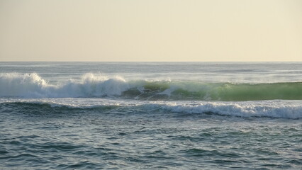 Obraz premium Powerful Emerald Waves Crashing During Early Morning. Dynamic close-up of emerald green ocean waves crashing with white sea foam under the soft morning light of a spring.