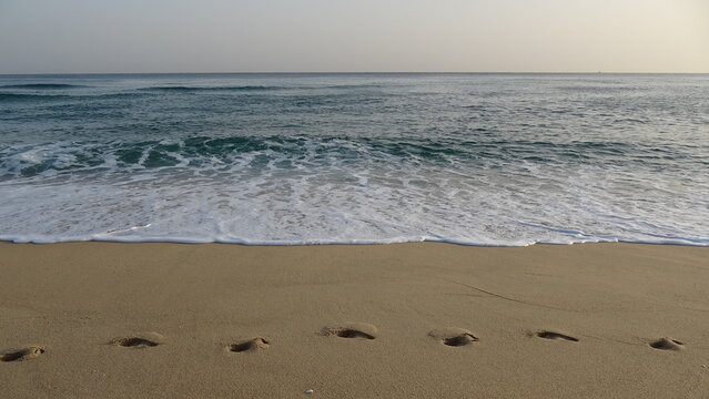 Footprints on Sandy Beach towards Tranquil Morning Sea.
A line of deep footprints left on the soft sand leading along the quiet shoreline during early morning light.