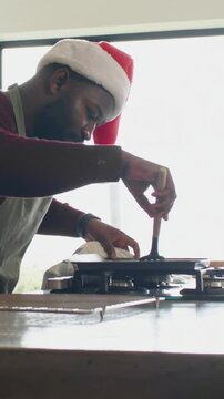 Vertical video: Flipping man in Santa hat and apron inserting spatula at gas stove, copy space