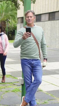 Vertical video: Checking phone, mature man in green top rising as woman nearing path giving flowers