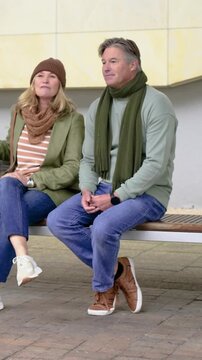 Vertical video: Talking couple on bench woman with coat rising, walking left after chat man seeing