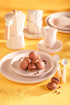 Tasty and fresh coffee macarons on plate on yellow background.