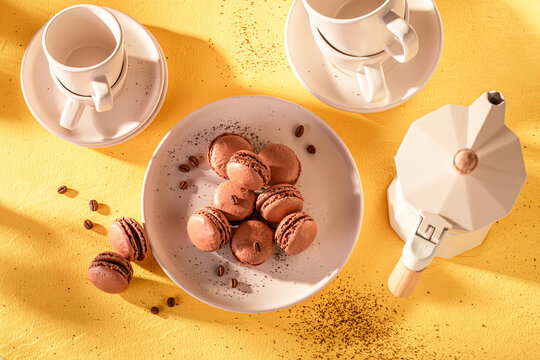 Creamy and homemade coffee macarons on plate on yellow background.