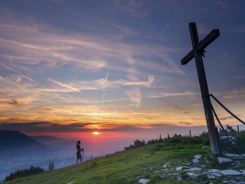 Young slim woman with hiking poles next to a summit cross at sunset, cirrus clouds in the sky, Schlenken, Bad Vigaun, Land Salzburg, Austria