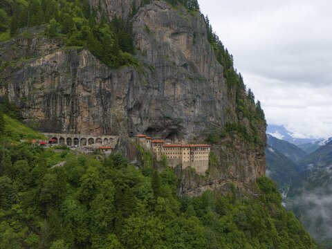 A monastery embedded in a steep rock face surrounded by lush forests and mountains under an overcast sky, aerial view, Sumela Monastery, S&uuml;mela Manastırı, Ma&ccedil;ka, Macka, Trabzon Province, Turkey