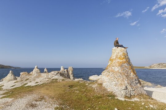 Hiker sitting on one of the legendary dolomite rocks on Porsangerfjorden fjord, near Lakselv, Porsanger, Pors&aacute;ŋgu, Porsanki, Finnmark County, Norway