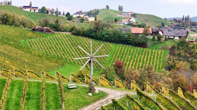 Aerial view of the Sudsteiermark vineyards with a traditional Klapotetz windmill and rolling hills under a clear sky in Gamlitz, Styria, Austria.