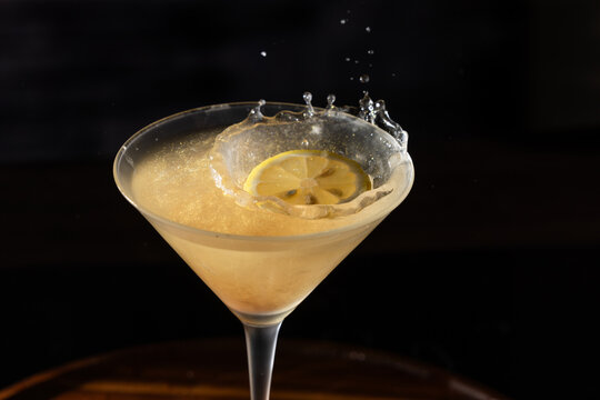 Dropping the garnish into a lemon drop cocktail creating a splash