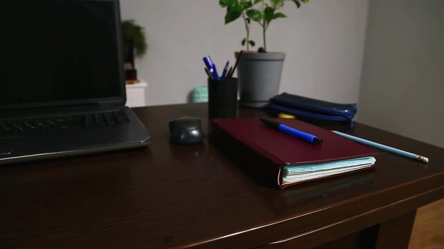 Office work desk with a wood table. Computer, notebook with blue pen, pencil and flower in pot in the study home room. Education, learning concept in different angles. Closeup