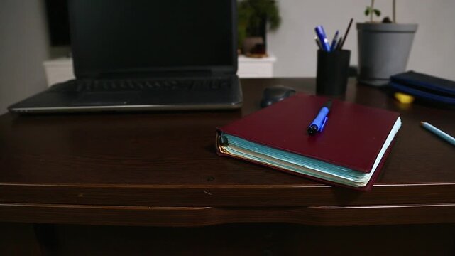 Office work desk with a wood table. Computer, notebook with blue pen, pencil and flower in pot in the study home room. Education, learning concept in different angles. Closeup