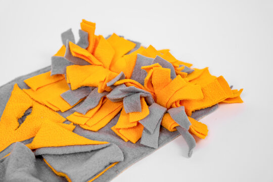 Orange and gray handmade felt snuffle mat unfolded on white background, pet dog enrichment toy product flatlay concept.