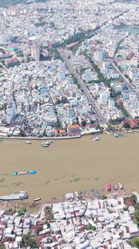 Vertical screen Aerial View Of Can Tho Dense Riverside Neighborhood With Close Packed Houses, Small Docks And Moored Boats, Narrow Lanes Leading To Waterfront Markets Mood Intimate, Lively