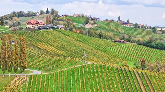 Aerial view of Sudsteiermark vineyards with rolling hills, traditional houses and a Klapotetz windmill in Gamlitz, Styria, Austria.