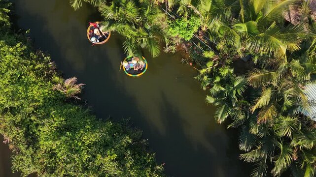 Couple Explores Boats. Tourists Paddle Along River Banks. Travelers Navigate Lush Canal With Paddles. Couple Enjoy Peaceful Boat Ride Through Vibrant Hillside Surroundings