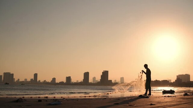 Asian Fisherman Walking And Casting Net Along Da Nang Shoreline At Sunrise Long Silhouette Against Glowing Sun Scattered Droplets Urban Skyline Motion And Solitude Amber Tones