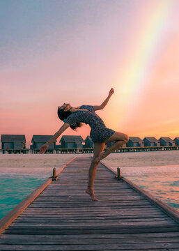 Joyful Woman Dancing on Wooden Pier at Sunset Beach Resort