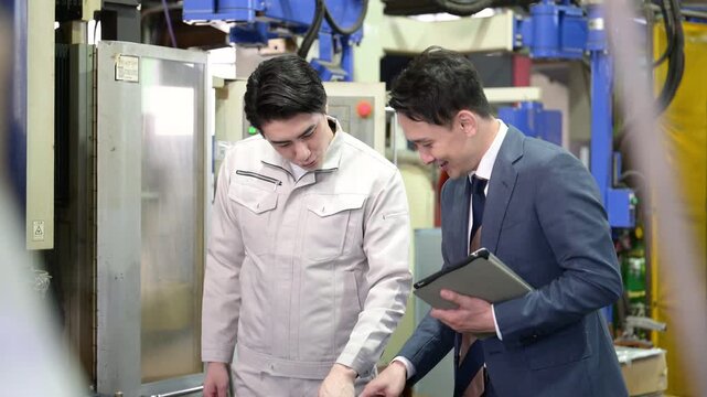 製造業の工場現場で作業着の技術者と営業が機械を見ながら見積もりや修理、メンテナンスの金額を前向きに相談する笑顔のポジティブイメージ動画