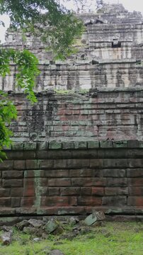 Ancient stone ruins of Koh Ker Pyramid Temple overgrown with moss and trees in Cambodia. The weathered stone blocks show signs of age and the encroaching jungle.