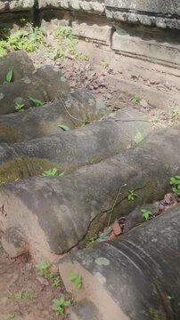 Ancient stone pillars lie scattered amidst overgrown vegetation at the ruins of Prasat Beng Mealea, Cambodia. The site showcases remnants of the pre-Angkorian Chenla Kingdom. ,
