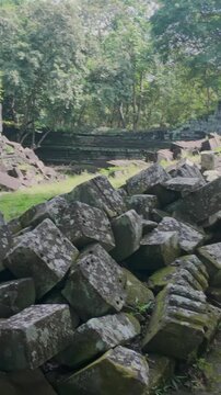 Ancient stone ruins of Beng Mealea temple, Cambodia, overgrown with trees and scattered with large rocks, showcasing the jungle's reclamation of the historic site.