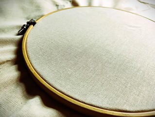 Single wooden embroidery hoop stretching blank white cotton fabric, copy space design © Caroline
