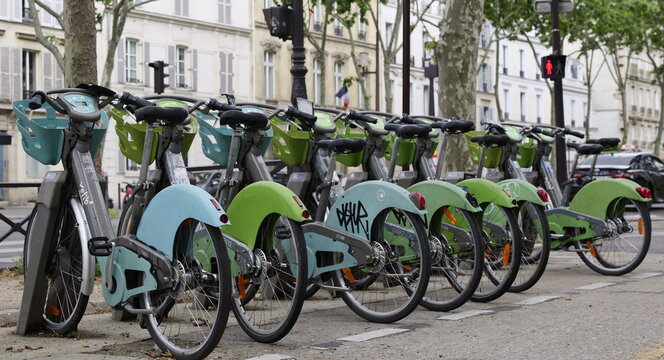Row of Velib' city rental bicycles parked at a docking station on a street in Paris France