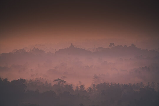 Misty Morning view of Borobudur with layers of trees seen from Setumbu, Indonesia