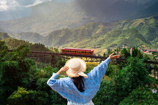 Female tourist watching train crossing and enjoying the mountain landscape and rice terraces in Sapa, Vietnam