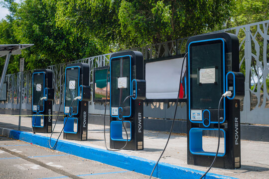 Several black and blue charging stations show white connectors plugged in and ready for recharging urban electric cars.