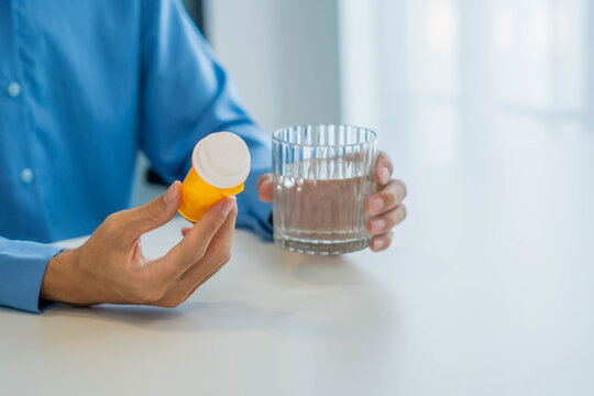 Patient holding medicine bottle and glass of water