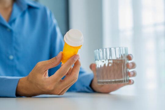 Patient holding medicine bottle and glass of water
