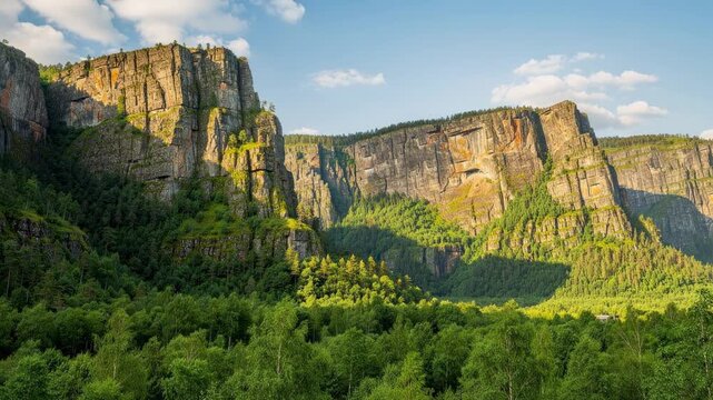 Scenic view of towering rocky cliffs with lush green forest under a clear blue sky