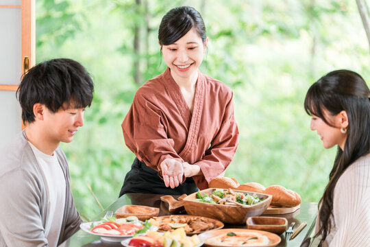 温泉旅館の客室で料理の説明をする旅館スタッフ・仲居さんの女性